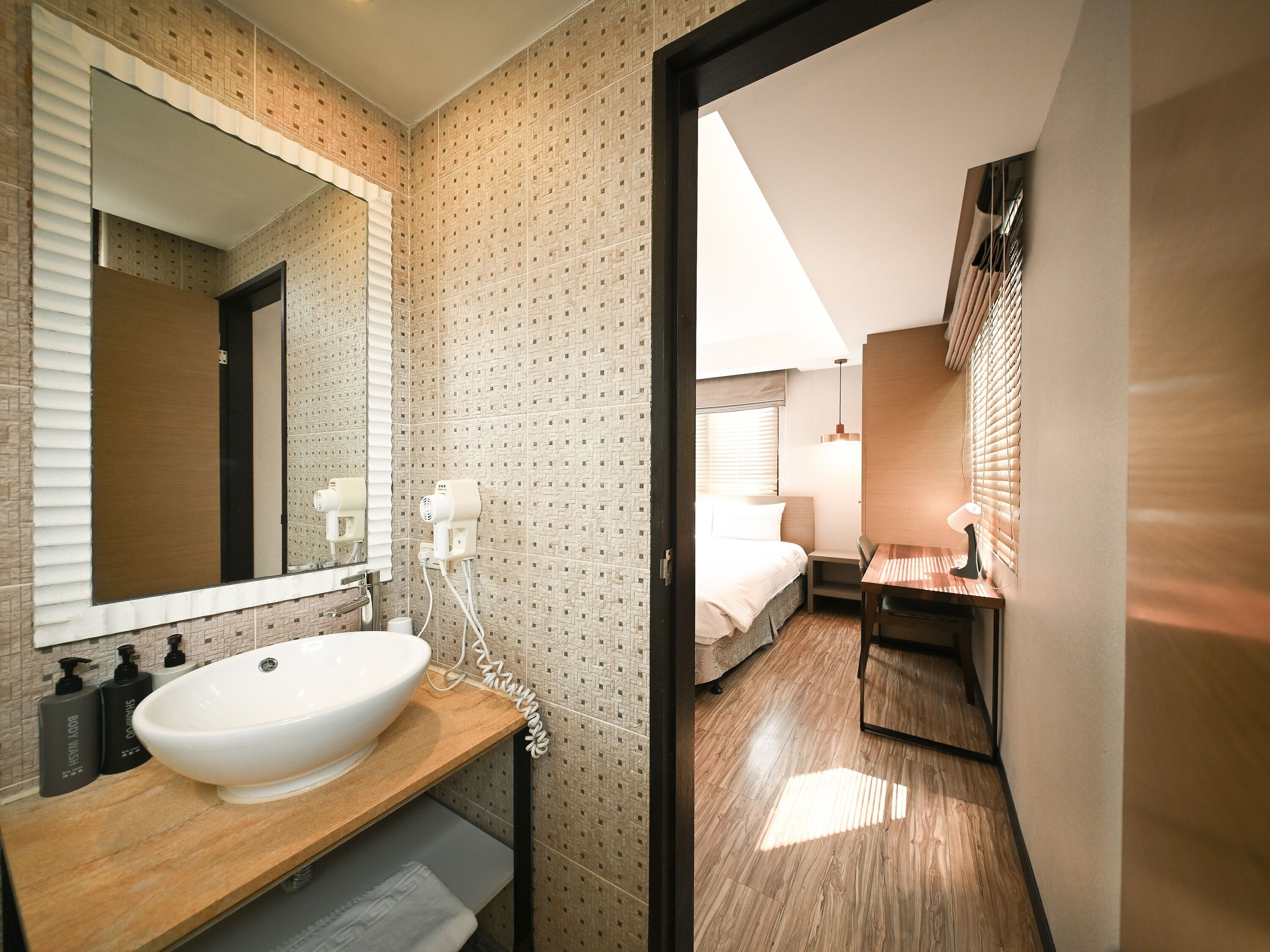 Un baño moderno con un espejo grande, lavamanos y dos secadores de pelo.