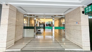 A hotel entrance with a check-in Express desk, a no-smoking sign, and a green directional sign. - CHECK inn Express Taipei Station (Taipei)