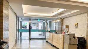 A hotel reception area with a modern design, featuring a reception desk, a printer, and a seating area. - CHECK inn Express Taipei Station (Taipei)