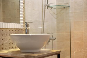 Une salle de bain avec un grand lavabo blanc, une douche en verre et des murs carrelés.