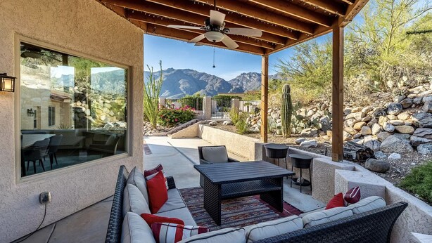 An outdoor patio with wicker furniture, a ceiling fan, and a view of mountains.