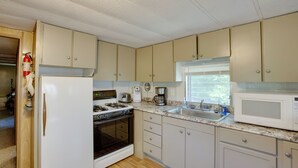 Una cocina con gabinetes color beige, un refrigerador blanco, una estufa, un microondas y un fregadero.
