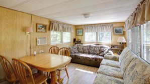 Una habitación acogedora con una mesa de madera, sillas, un sofá y una ventana con cortinas.