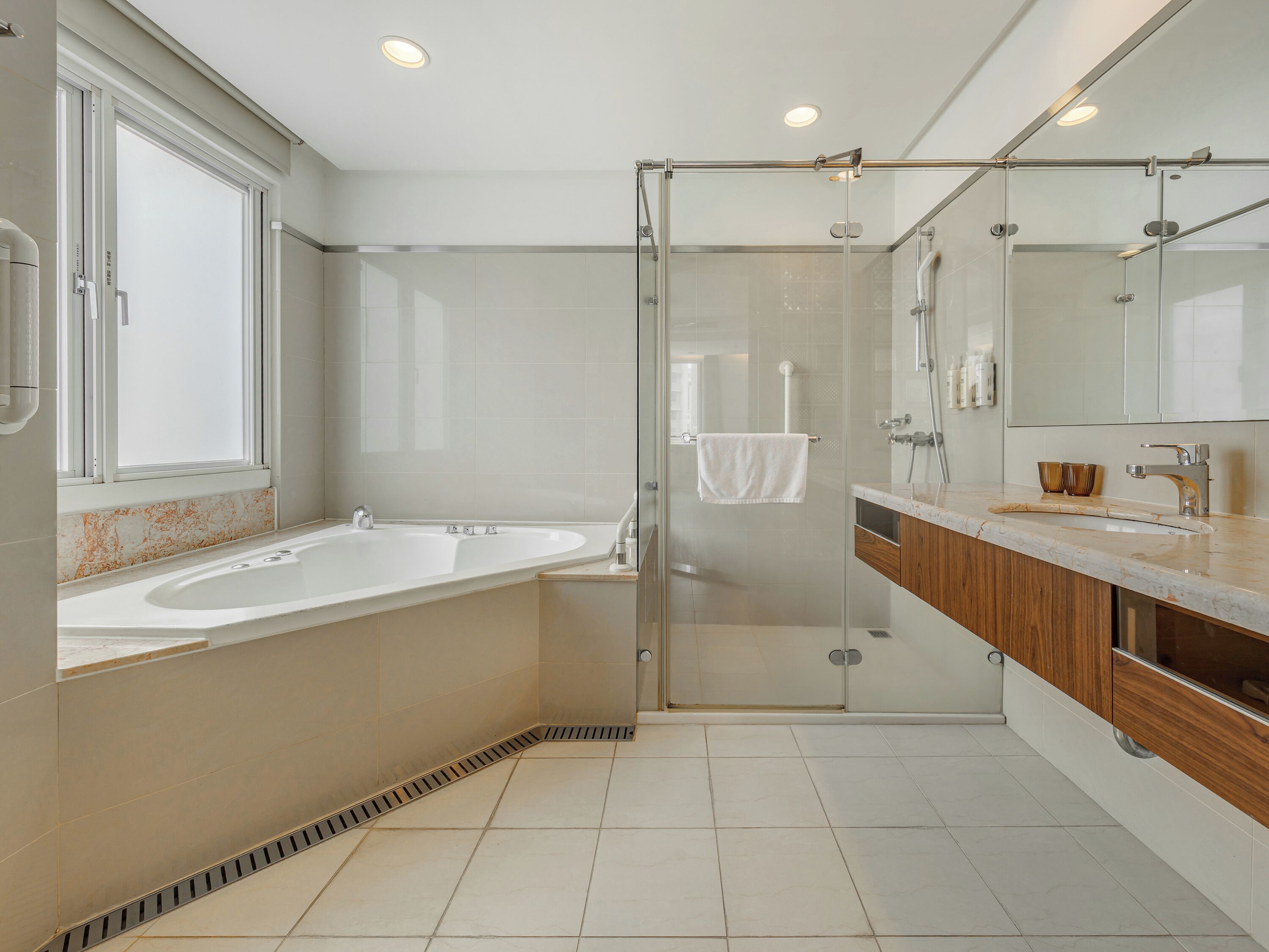 Un baño moderno con ducha de vidrio, una bañera independiente y un tocador con espejo.