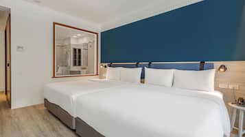 A hotel room with a large bed, a mirror, a bedside table with a lamp, and a view of the bathroom.