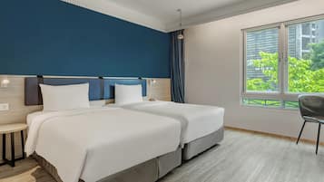 A hotel room with two beds, a nightstand, a chair, a window with a view of greenery, and a ceiling light.