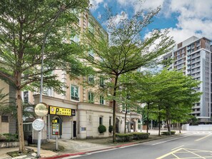 A street view with a building that has a parking sign, a tree-lined sidewalk, and a clear sky. - CHECK inn Select Taipei Nangang (Taipei)