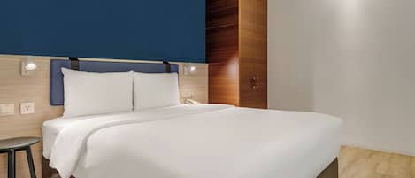 Una habitación de hotel moderna con una cama grande, una mesita de noche y un armario.