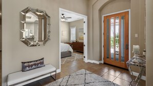 Un couloir avec un banc, un miroir et une porte donnant sur une chambre à coucher.