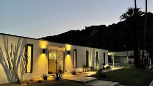 Una casa moderna con un vestíbulo bien iluminado, un camino de entrada pavimentado y un jardín ajardinado.