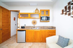 A compact kitchen with wooden cabinets, a microwave, a built-in oven, and a small refrigerator.
