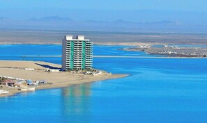 A high-rise hotel with a beach view, located near a body of water.