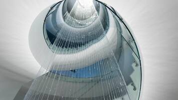 A modern architectural structure with a glass facade and a central water feature.