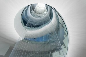 Una estructura arquitectónica moderna con fachada de vidrio y un elemento central de agua.