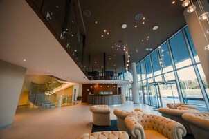 Un'ampia hall con una reception centrale, una scala e grandi finestre che offrono vista.