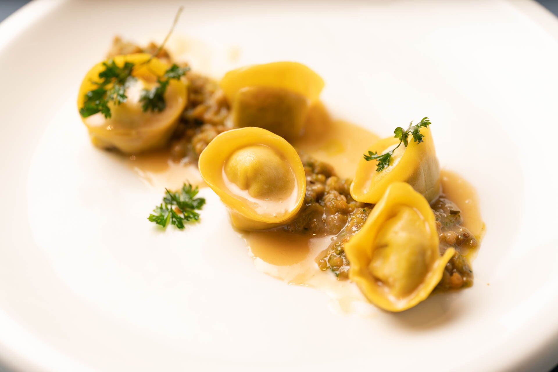 Une assiette de raviolis, accompagnée d’une sauce et d’une garniture.