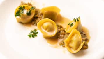 Une assiette de raviolis, accompagnée d’une sauce et d’une garniture.