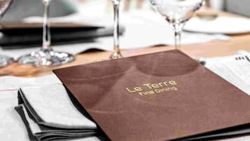 Una mesa dispuesta con copas de vino y un menú en Le Tore Fine Dining.