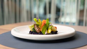 A plate of colorful vegetables on a white plate with a dark mat underneath, set on a wooden table.
