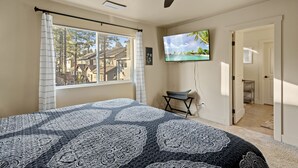A bedroom with a bed, a ceiling fan, a TV on the wall, and a window with curtains. - Pico in the Pines, pet friendly and cozy fireplace (Flagstaff)