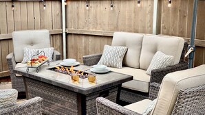An outdoor patio with wicker furniture, a fire feature, and string lights. - Pico in the Pines, pet friendly and cozy fireplace (Flagstaff)