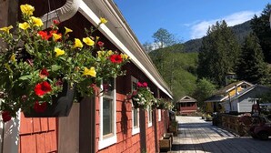 A row of red wooden buildings with hanging flower baskets.