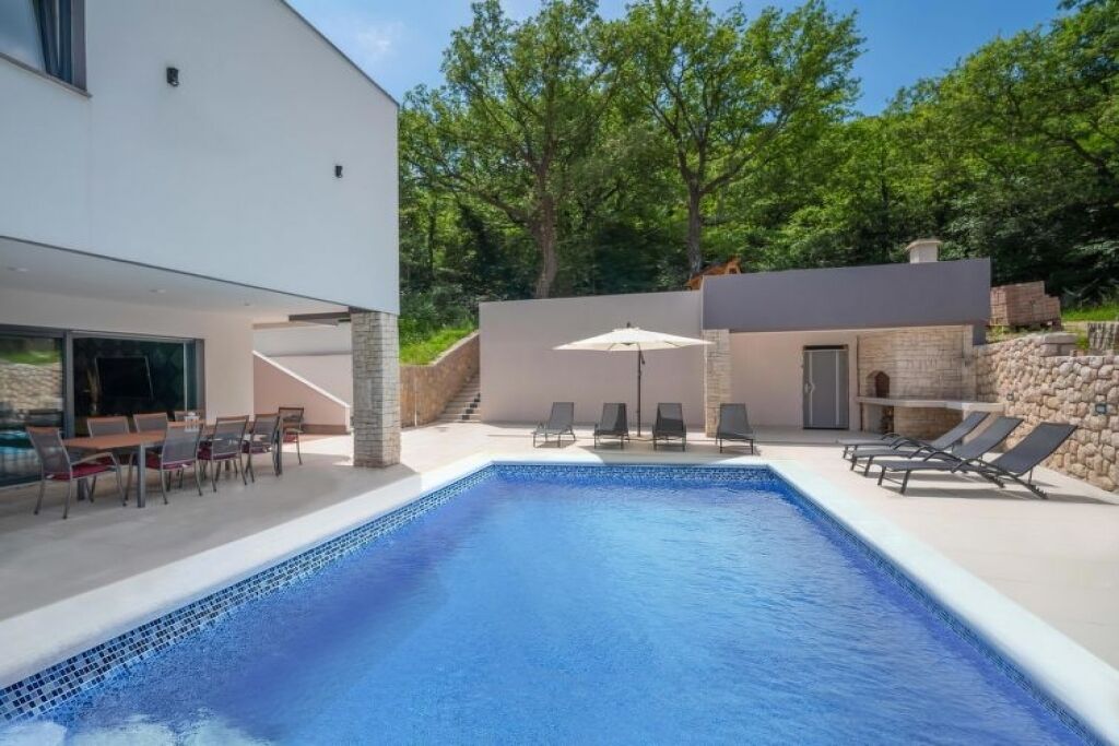 A modern pool area with lounge chairs and a dining setup.
