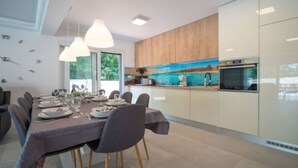 Eine moderne Küche mit Holzschränken, einem Einbauofen und einem Essbereich mit Tisch für sechs Personen.
