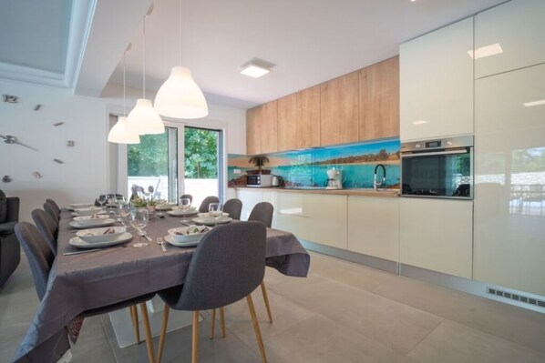 A modern kitchen with wooden cabinets, a built-in oven, and a dining area with a table set for six.