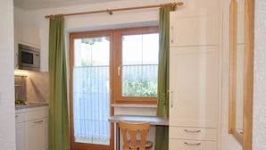 Cocina compacta con microondas, una mesa de madera, una silla y un armario.