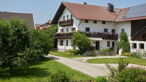Un edificio de estilo europeo tradicional con techo inclinado, un balcón con jardineras y un camino de grava que conduce a la entrada.