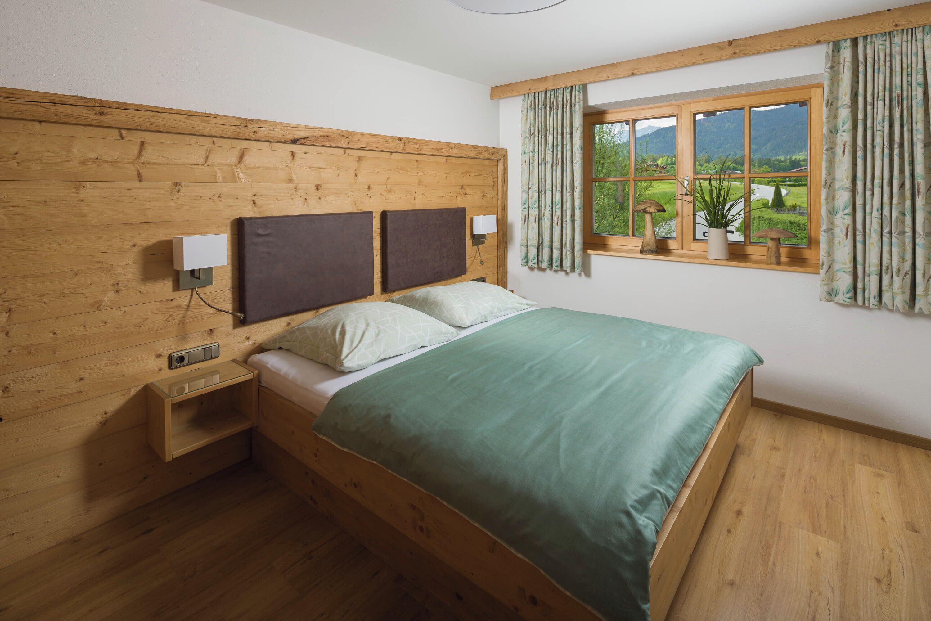 Una camera da letto con pannelli in legno, un letto, comodini e una finestra con tende.