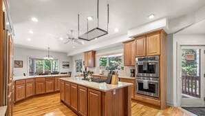 A spacious kitchen with wooden cabinets, a large island, stainless steel appliances, and a view of the outdoors.