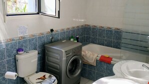 A compact bathroom with a toilet, washing machine, and two sinks. - Rental with swimming pool, close to beaches, at the foot of the maquis. (Biguglia)