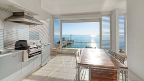 A balcony with a view of the sea and a grill area with a table and chairs. - Deep Blue 12 - Tangalooma - Moreton Island (Moreton Island)