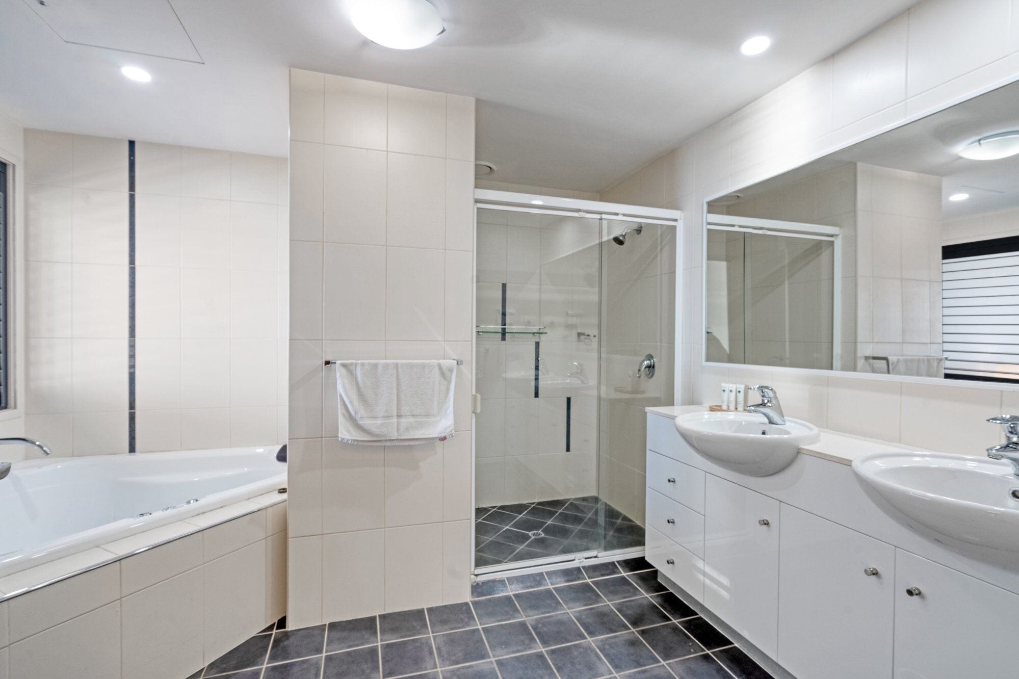 Une salle de bain moderne équipée d’une baignoire, d’une zone de douche et d’un meuble-lavabo avec un évier.