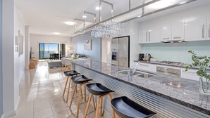 A modern kitchen with a central island, stainless steel appliances, and a view to the outside. - Deep Blue 12 - Tangalooma - Moreton Island (Moreton Island)