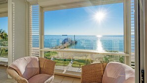 A balcony with wicker chairs, a view of the sea, and a pier. - Deep Blue 12 - Tangalooma - Moreton Island (Moreton Island)