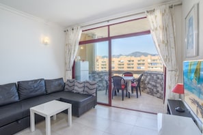 A balcony with a sofa, a table, and a dining area with chairs and a table.