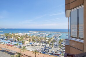 Un puerto deportivo con barcos amarrados, una zona de estacionamiento y vista al mar.