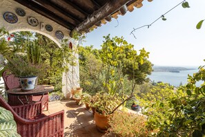 A patio with wicker furniture, potted plants, and a view of the sea. - Villa 'Paraíso Azul' with Sea Views, Wi-Fi and Air Conditioning (Salobreña)