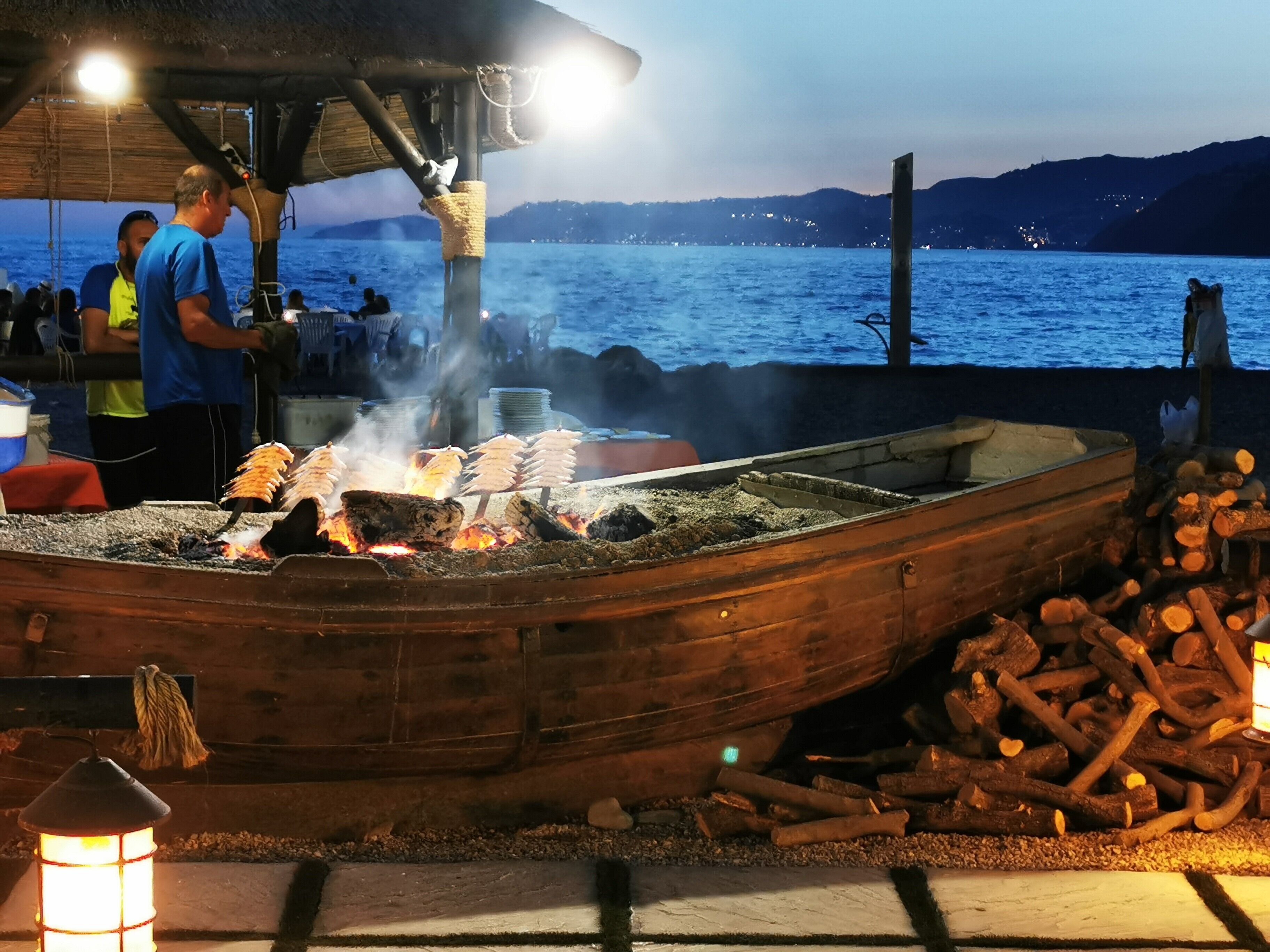 Un barco de madera con una parrilla, leña y un farol.