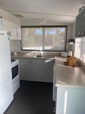 Compact kitchen with central island, sink, and toaster, offering a view of the outdoors.