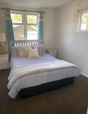 Relax in this serene bedroom with a large bed, bedside table, and window above.