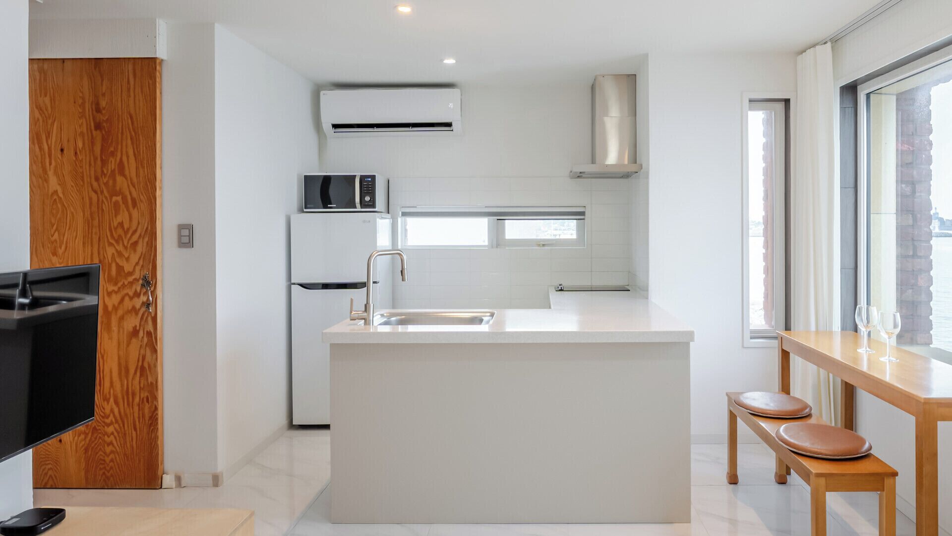Uma cozinha moderna com uma ilha central, eletrodomésticos embutidos e uma grande janela que oferece luz natural.