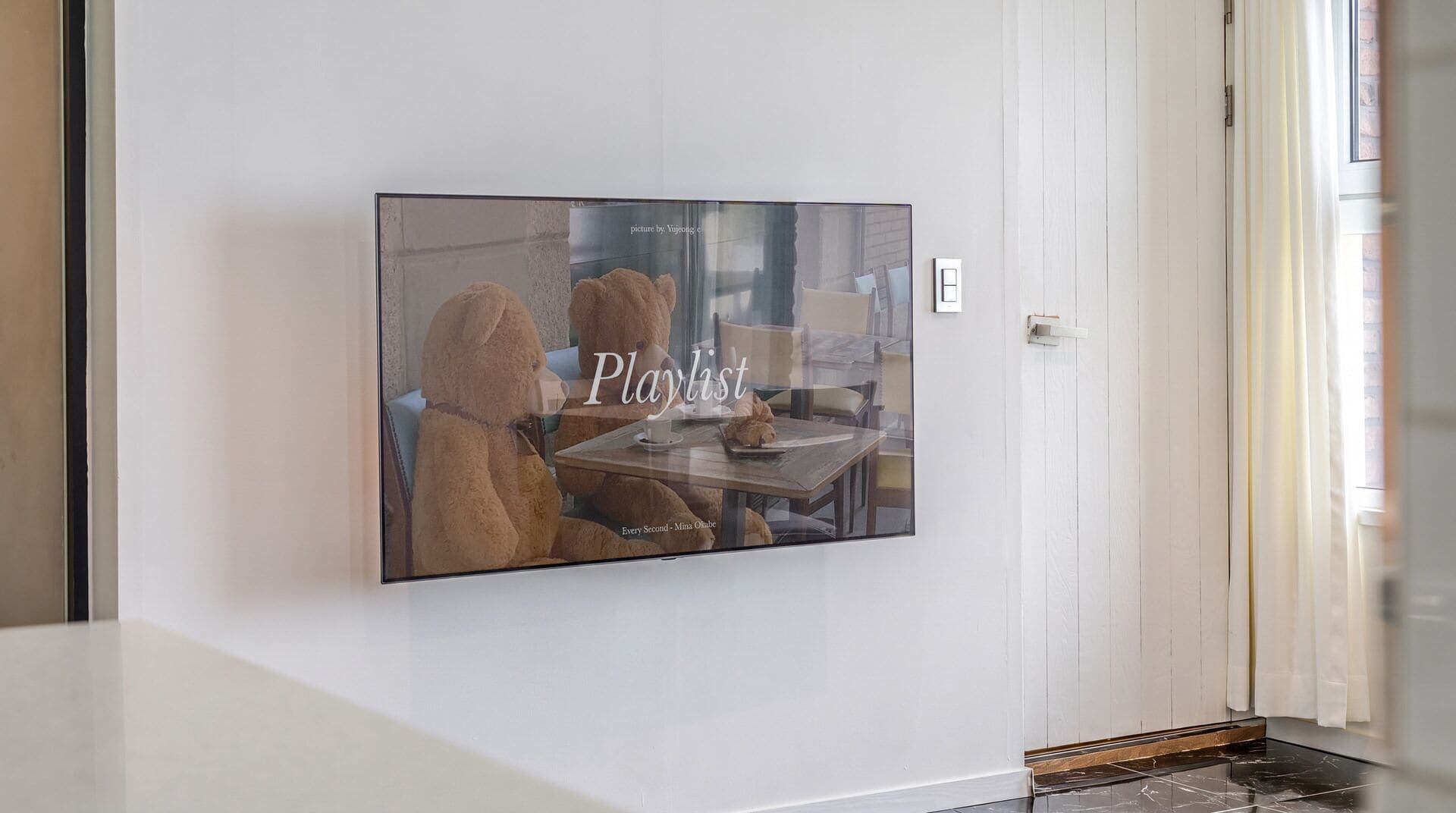 Una obra de arte enmarcada en una pared, con el texto 'Playlist' y 'Every Second - Mina Olube' a la vista.