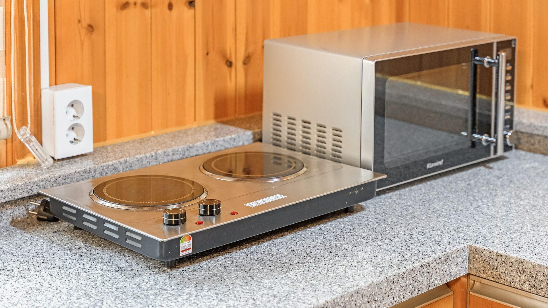 Une cuisine équipée d’un four à micro-ondes encastré et d’une plaque de cuisson à induction.