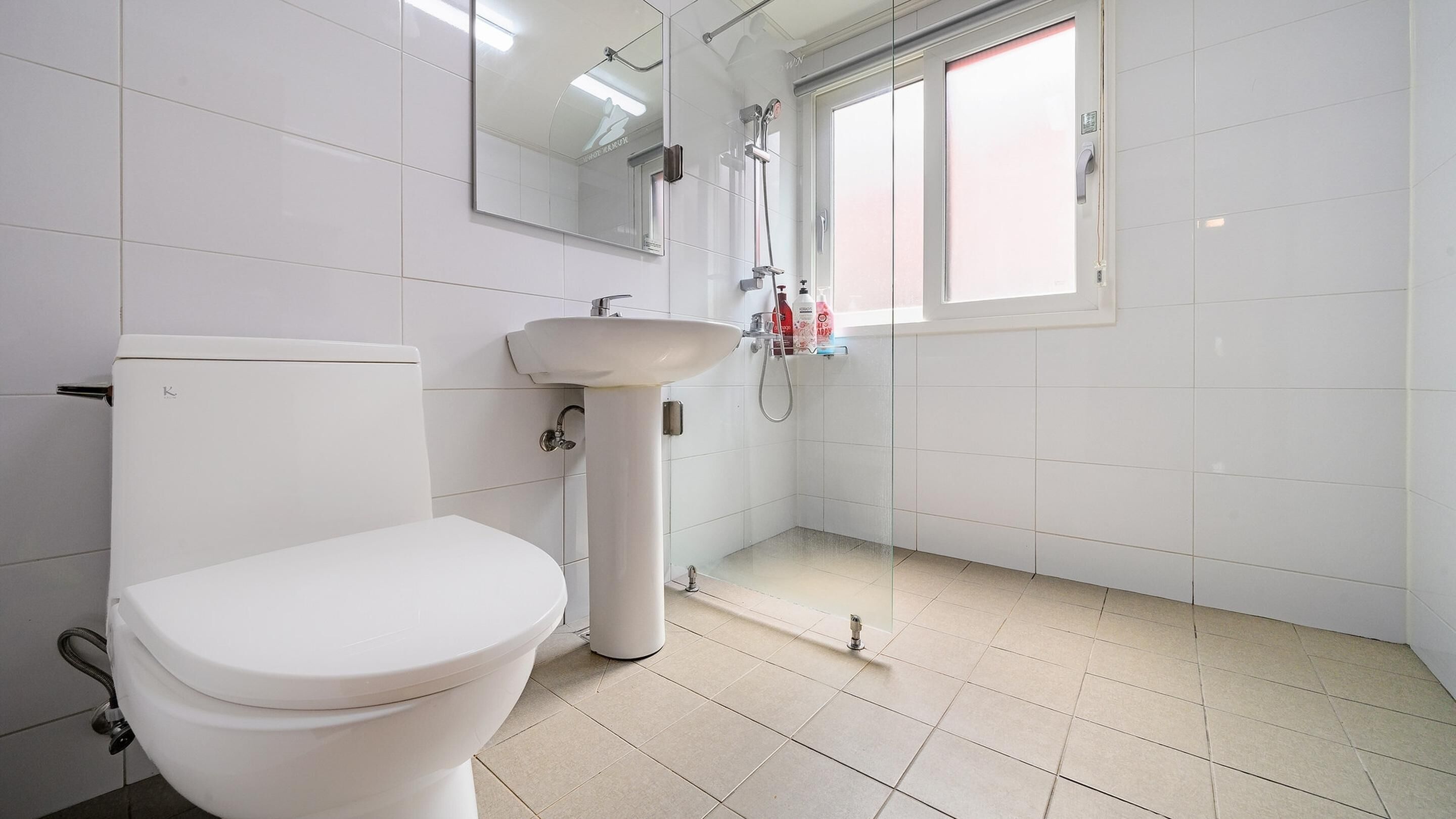 A bathroom with a toilet, sink, and shower.
