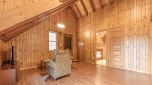 A spacious attic room with wooden walls and a sloped ceiling.