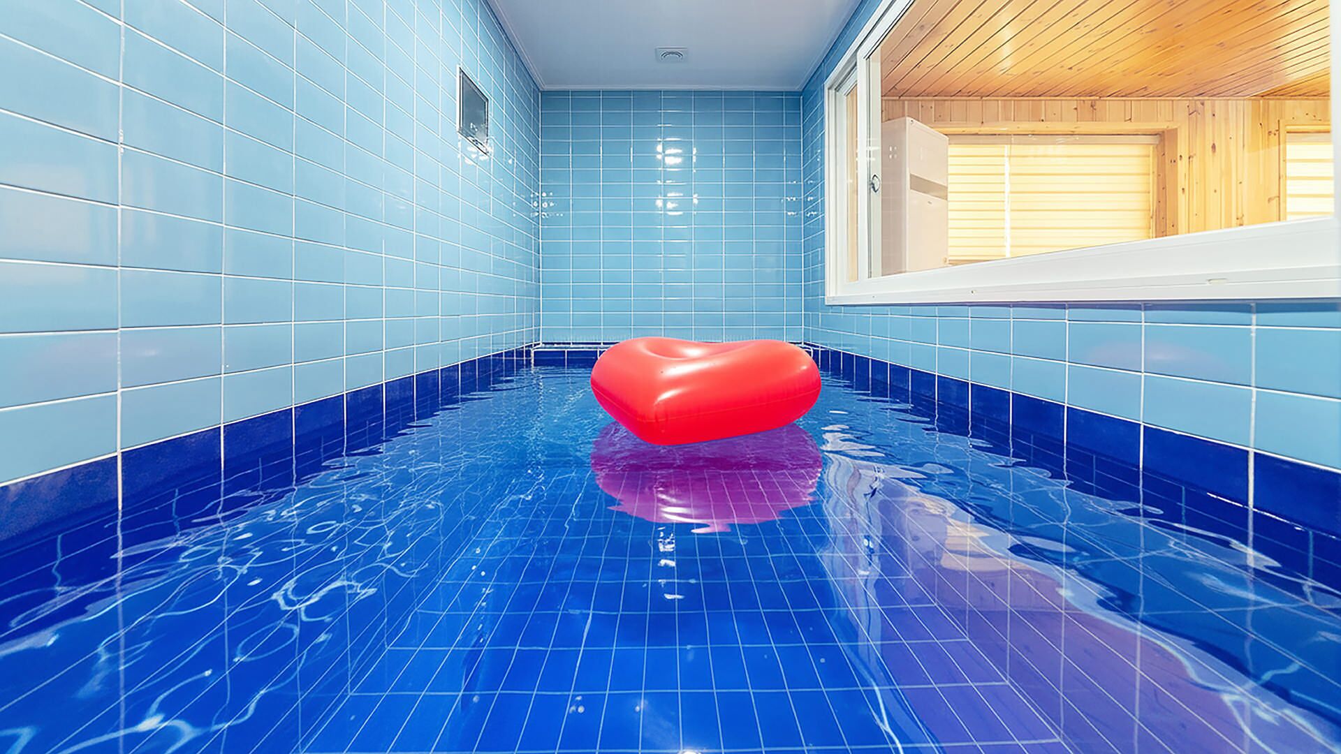 A swimming pool with blue tiled walls and a wooden ceiling.